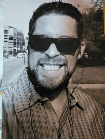 A man with sunglasses and beard smiling for the camera.