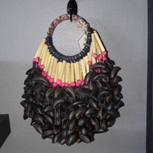 Handcrafted tribal necklace featuring beads, bamboo, and wooden elements displayed on a wall hook.